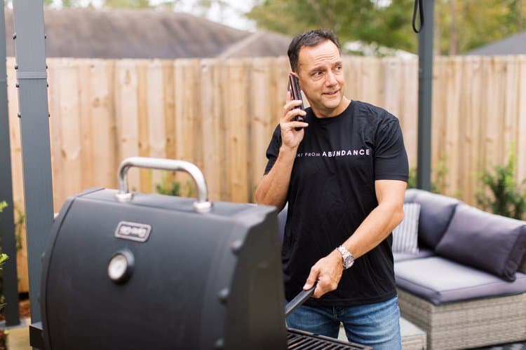 A man grilling while talk to the phone